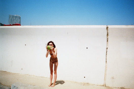 Woman wearing swim suit eating watermelon