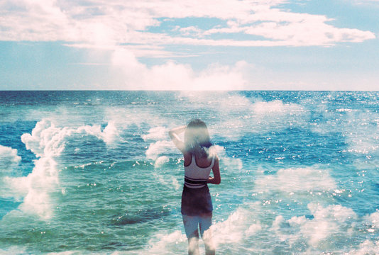 Girl standing by the ocean on a warm summer day filled with clouds