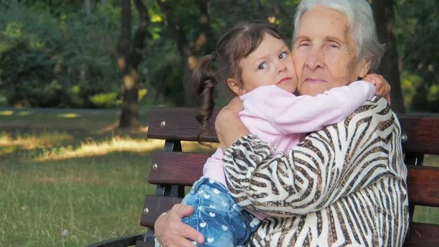 A little girl is hugging an elderly woman. Granddaughter embraces his grandmother.