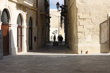 Fototapeta na wymiar Tourists on a narrow street of an ancient city. Lecce, Apulia, Italy