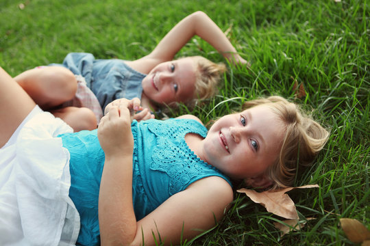 Sisters Laying In Grass Laughing