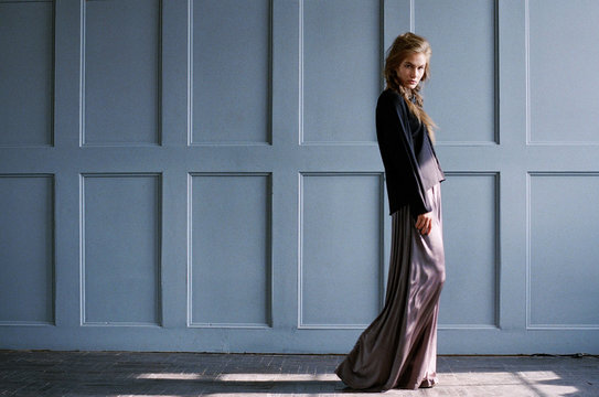 Young woman walking along light-blue wall