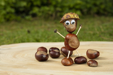 Funny human shape character or figurine made with chestnuts on a wooden background in a sunny day