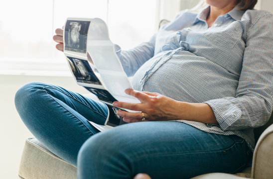 pregnant woman holding ultrasound images