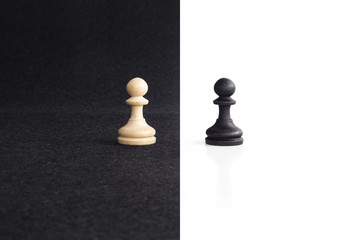 Pair of peon chess peaces confronted as opposites in black and white background - obrazy, fototapety, plakaty