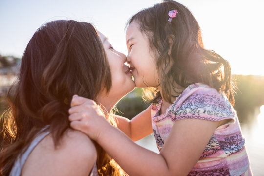 Happy Asian girl kissing her mother