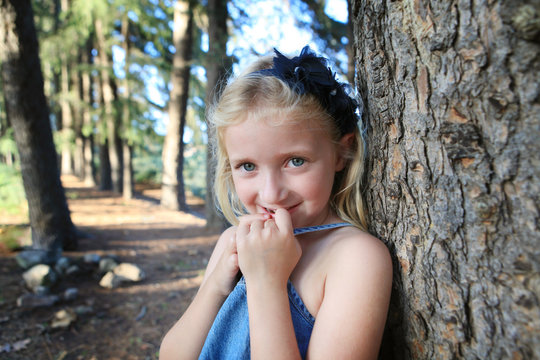 Little Blonde Girl In Forest With Blue Eyes