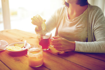 close up of woman adding lemon to tea cup