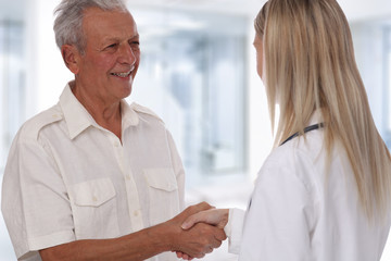 Smiling female doctor giving handshake to senior male patient. Healthcare concept