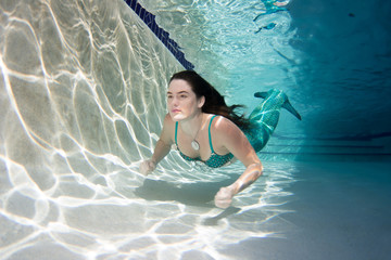 Woman wearing a bikini swimsuit holding her breathe underwater.