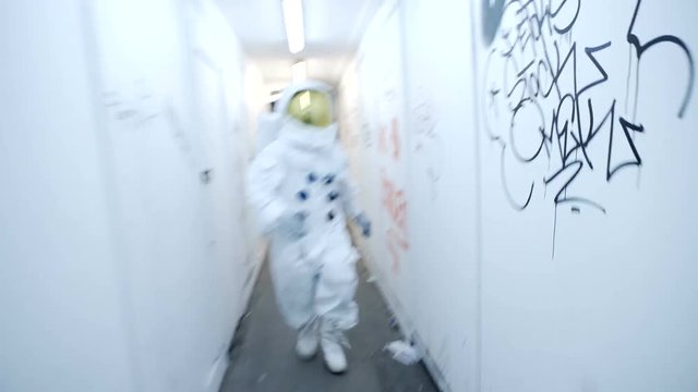  Astronaut in urban environment, running through building with graffiti on wal
