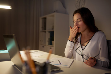 tired woman with papers yawning at night office