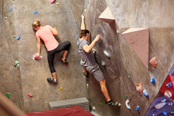 man and woman training at indoor climbing gym wall