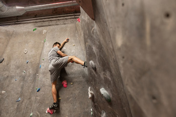Obraz na płótnie Canvas young man exercising at indoor climbing gym wall