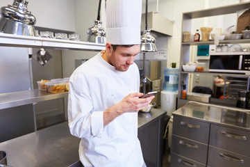 chef cook with smartphone at restaurant kitchen