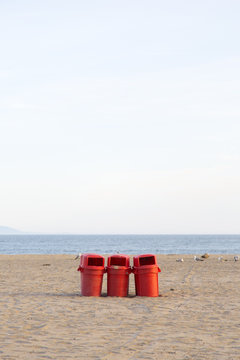 Red trash cans on a beach