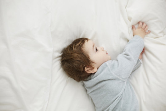 Toddler in a dreamy mood lying on the bed
