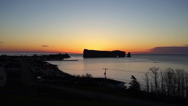 Famous Rocher Perce rock in Gaspe Peninsula, Quebec, Gaspesie region with cityscape at colorful sunrise, dawn