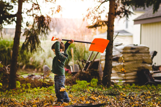 Boy Holding A Shovel Overhead While Doing Yardwork