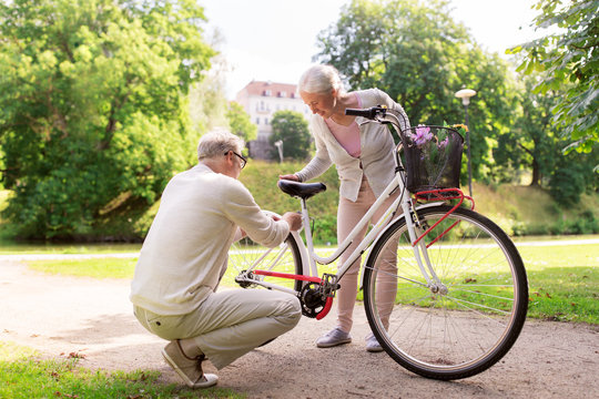 happy senior couple with bicycle at summer park