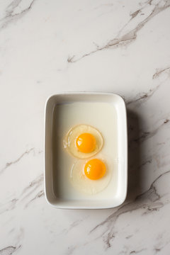 two raw eggs in a rectangle dish