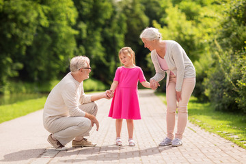 senior grandparents and granddaughter at park