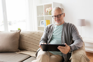 senior man with tablet pc sitting on sofa at home