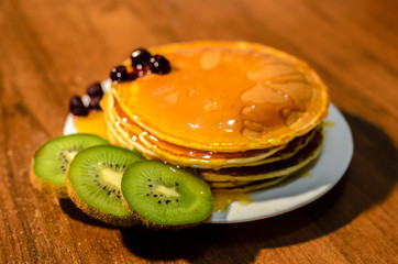 Delicious pancakes with honey, kiwi and berries.