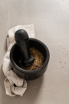 A pestle and mortar with cumin seeds