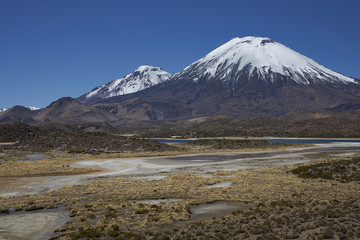 Fototapeta na wymiar Volcanoes Parinacota and Pomerape in Lauca National Park high on the Altiplano of northern Chile. In the foreground lakes known as Lagunas de Cotacani