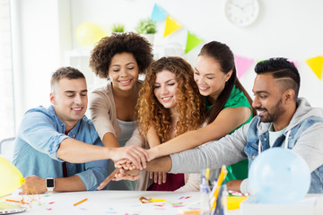 happy team at office party holding hands together