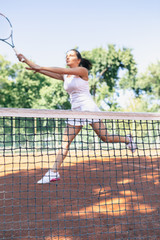 Beautiful young female tennis player playing tennis on court.