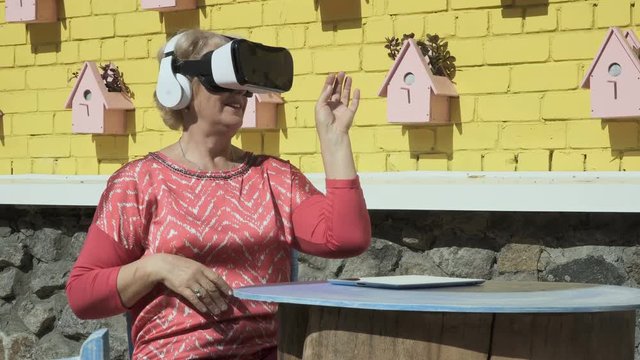 Pretty old woman uses virtual reality glasses