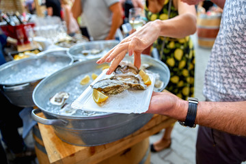 close-up of an oyster with a lemon, like snacks. woman is pickin