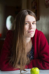 Fototapeta premium Portrait of young beautiful long-haired woman with apple in a red jacket.