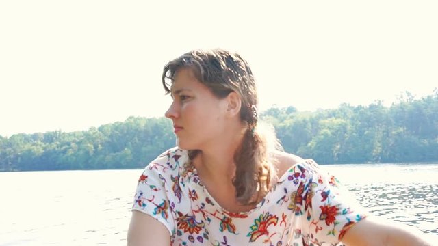 Serious focused concentrated young woman rowing boat on lake in Virginia during summer with warm, soft sunlight, sunshine, sun