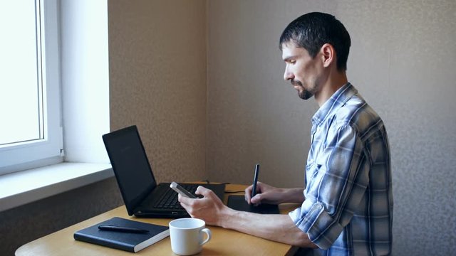 Young man sitting laptop and looking phone
