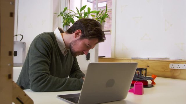 Designer working beside a 3D printer in a design studio, shot on R3D