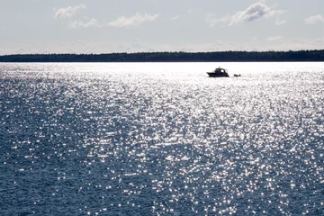 Schilderijen op glas Silhouette of a boat in a sunny reflection in Lake Superior © karagrubis