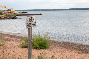Beach ends here sign with construction equipment behind