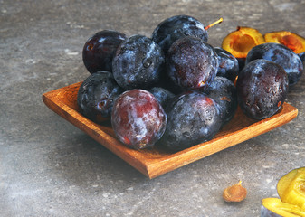 Fresh tasty blue plums on the wooden plate