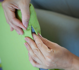 A woman sews a bright cloth with a needle. Manual sewing. Needlework.