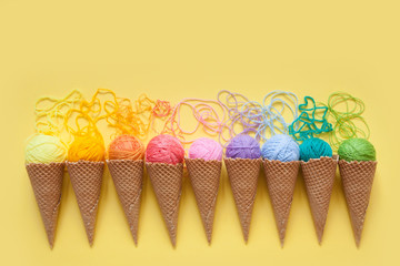 Balls of yarn lie in a waffle cone for ice cream. Coloured wool.