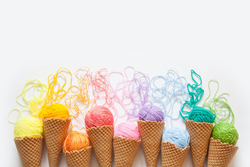 Balls of yarn lie in a waffle cone for ice cream. Coloured wool. - obrazy, fototapety, plakaty