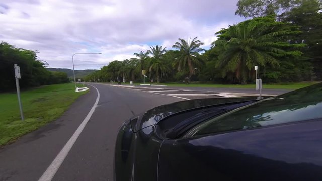 A gopro shot that is mounted on a car. The car exits a roundabout. The shot is taken under a cloudy day.