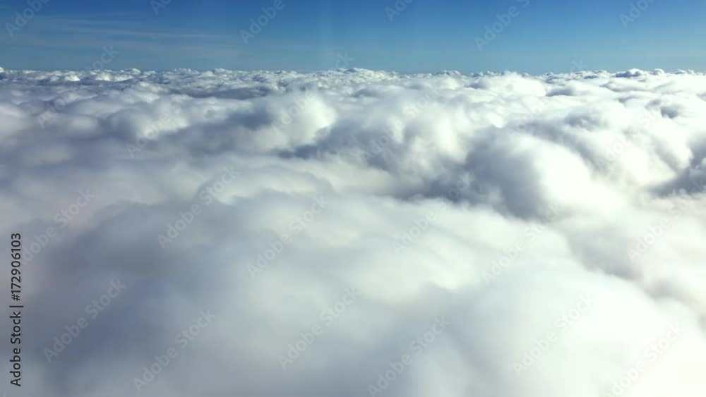 Wall mural aerial view flying over a layer of textured puffy clouds