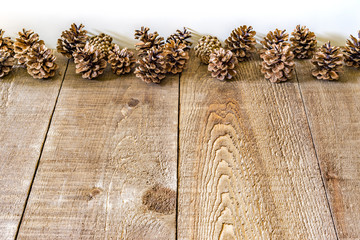 Rustic wood planks and a line of pinecones with white background