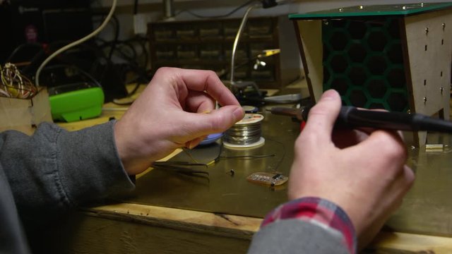 Man soldering wire to a circuit board, close up of hands, shot on R3D