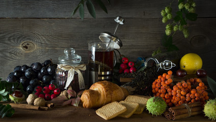Hot tea jug on a wooden background surrounded by autumn fruits