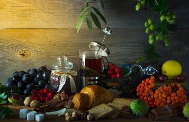 Hot tea jug on a wooden background surrounded by autumn fruits